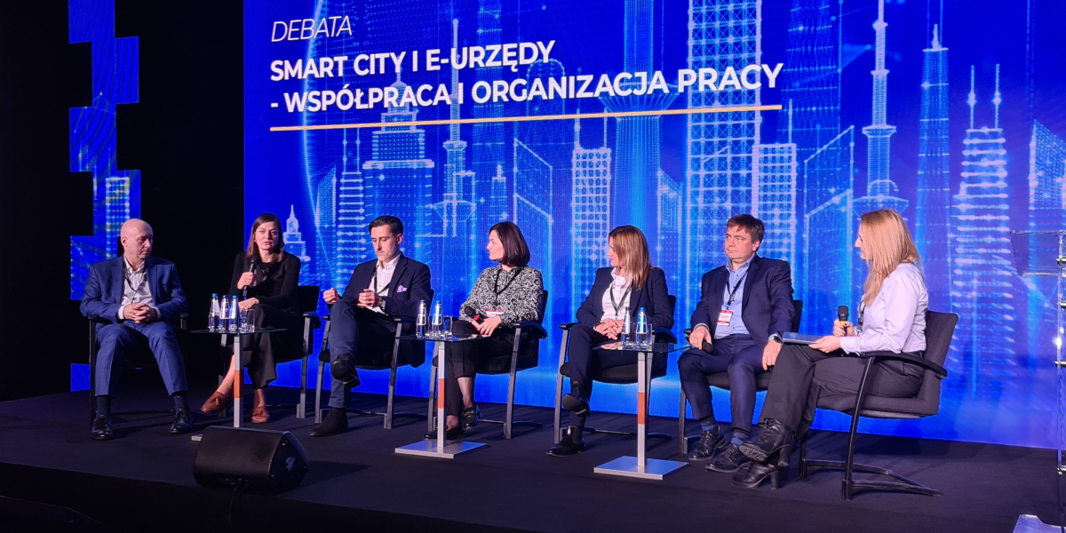 Grupa osób siedzących na scenie w półokręgu
