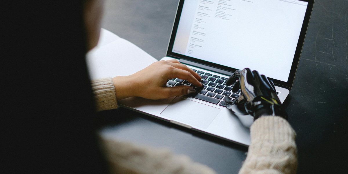 Laptop i pracujące na nim dłonie - prawdziwa i sztuczna
