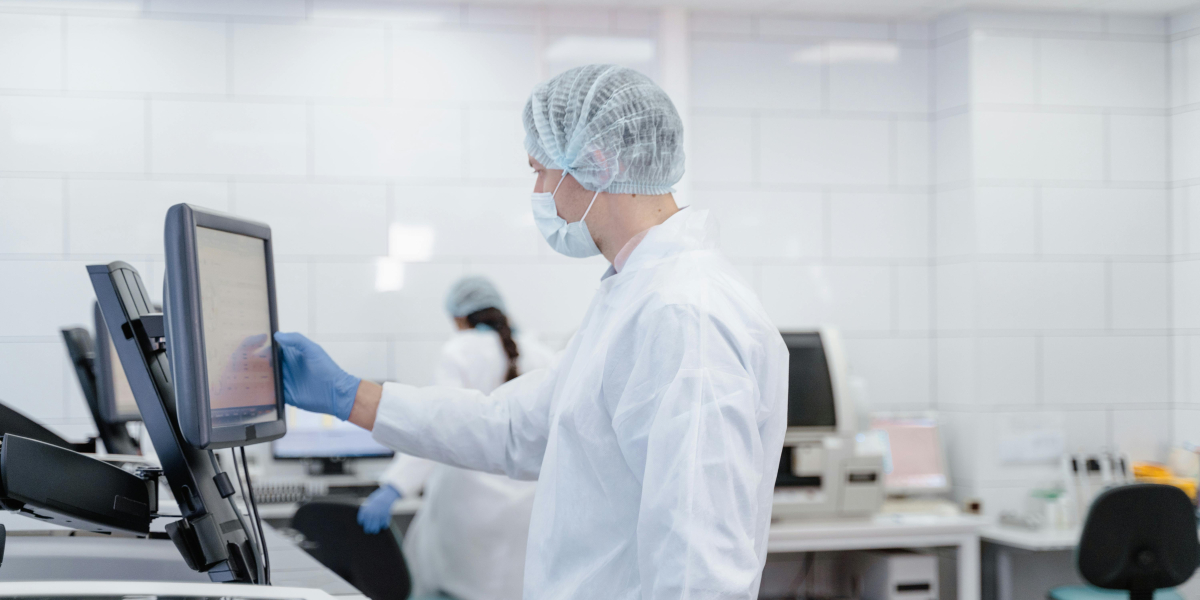 Mężczyzna w stroju laboratoryjnym klikający na ekranie dotykowym
