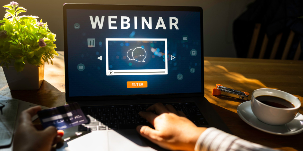 Laptop stojący na biurku i wyświetlający napis "WEBINAR"