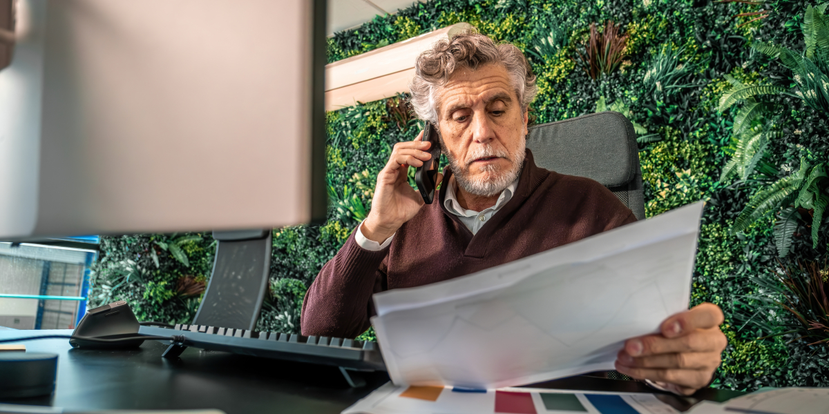 Mężczyzna rozmawiający przez telefon w biurze, w którym jest dużo roślin.