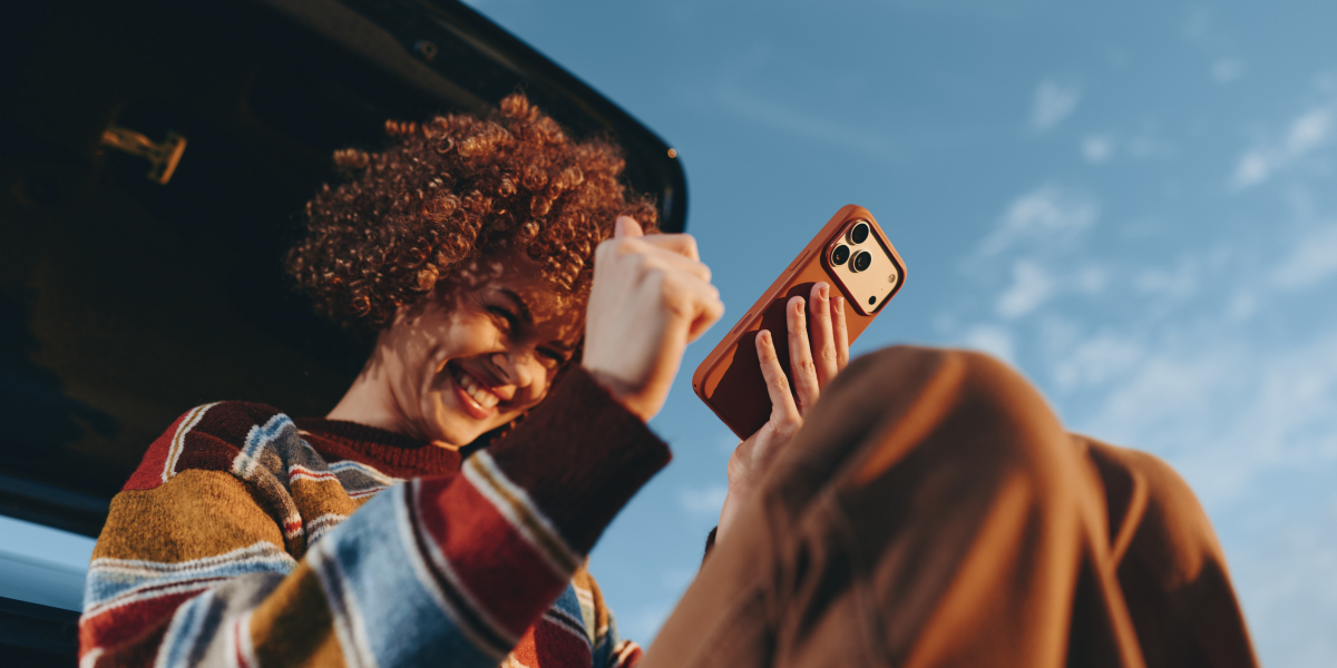 Młoda kobieta o kręconych włosach dokonuje zakupu na smartfonie
