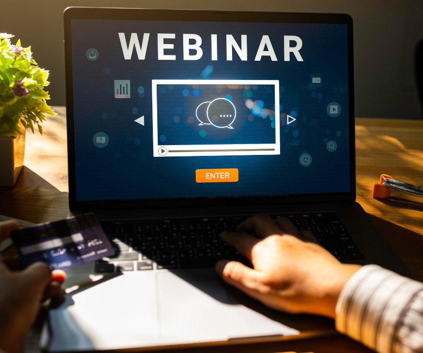 Laptop stojący na biurku i wyświetlający napis "WEBINAR"