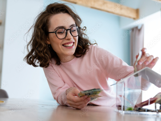 Kobieta wrzucająca pieniądze do skarbonki