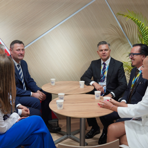 Grupa elegancko ubranych osób dyskutujących przy wspólnym stole.