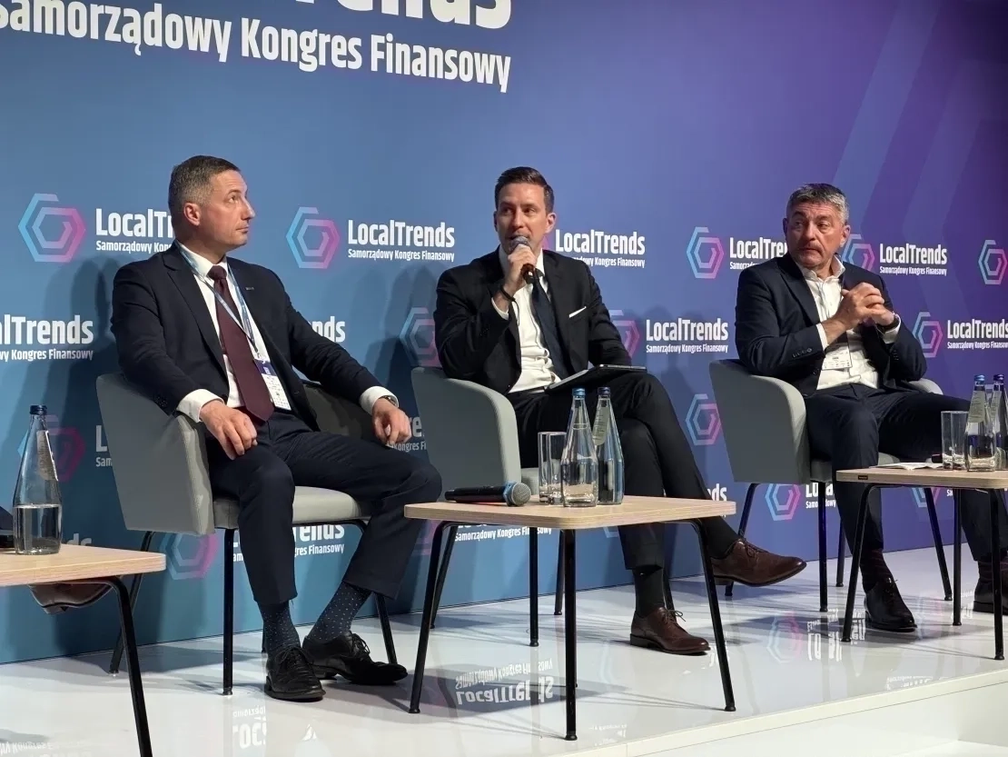 Trzech mężczyzn siedzących na krzesłach na scenie