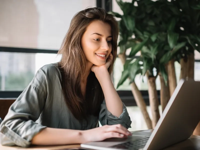 uśmiechnięta kobieta patrząca w ekran laptopa